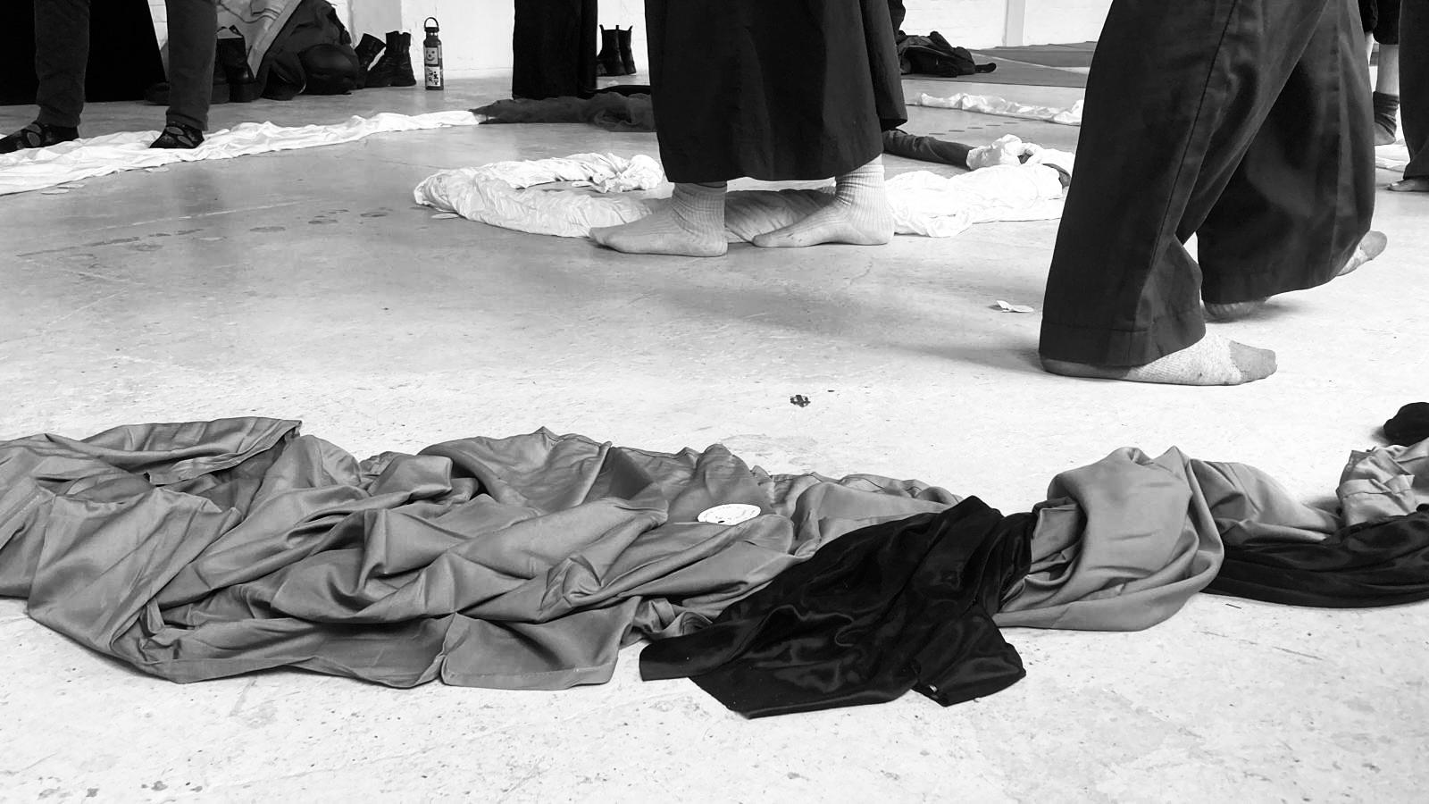 Participants standing barefoot around fabrics spread on the floor