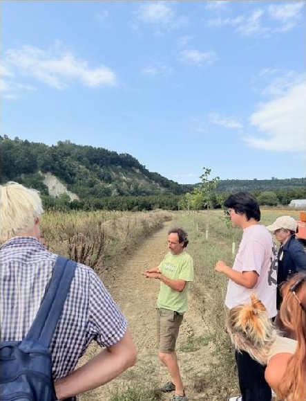 A facilitator addressing a group on a track between fields
